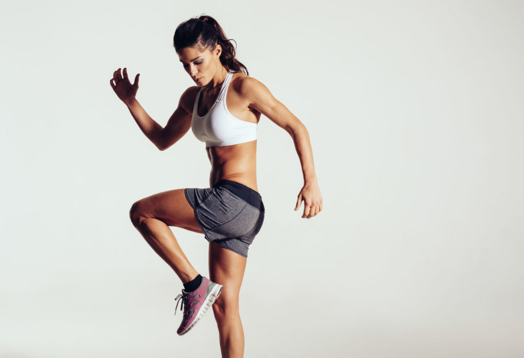 35753749 - attractive fit woman exercising in studio with copyspace. image of healthy young female athlete doing fitness workout against grey background.