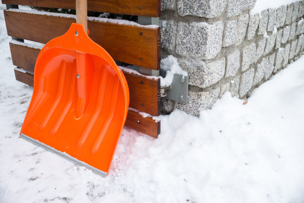 51302774 - snow removal. orange shovel in snow, ready for snow removal, outdoors.