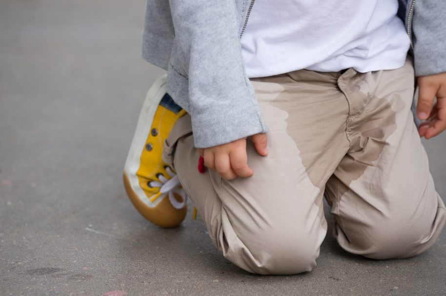 A young kid peeing on his pants on the street Bedwetting concept