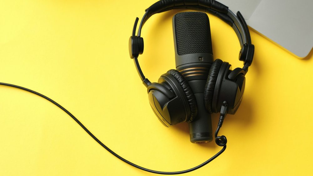 Flat lay composition with Microphone for podcasts and black studio headphones