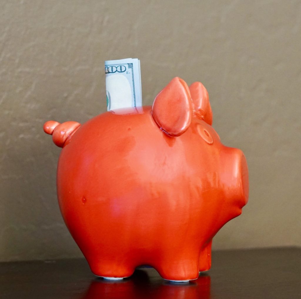 Cash sticking out of a red piggy bank