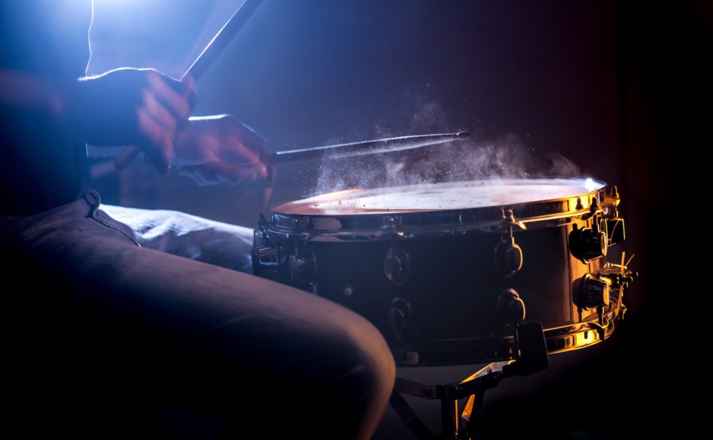 man playing the snare drum on a beautiful colored background