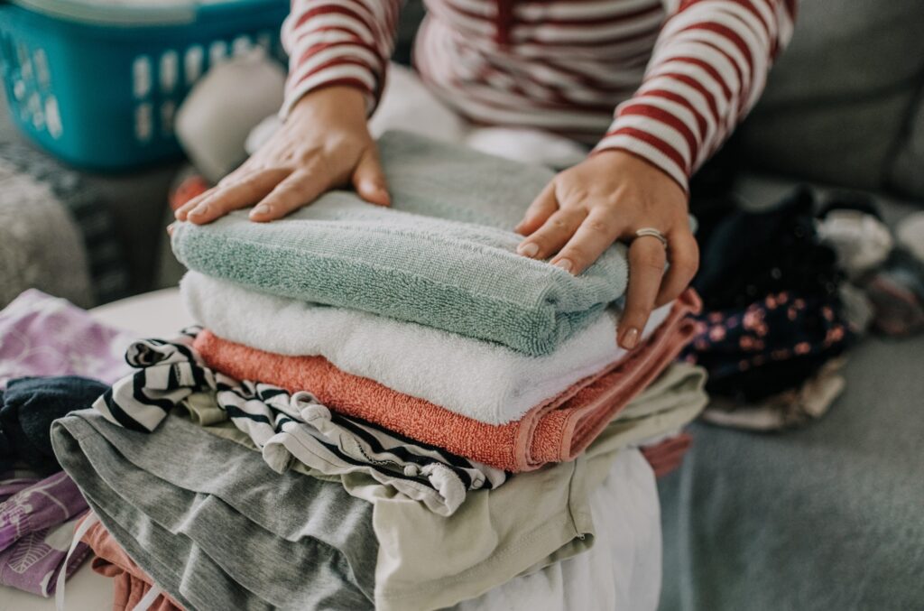 Close-up photo of woman folding laundry on sofa